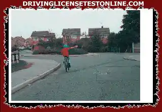 Se está acercando a esta rotonda . ¿Qué debe hacer cuando un ciclista se mantiene a la izquierda mientras le indica que gire a la derecha? ?