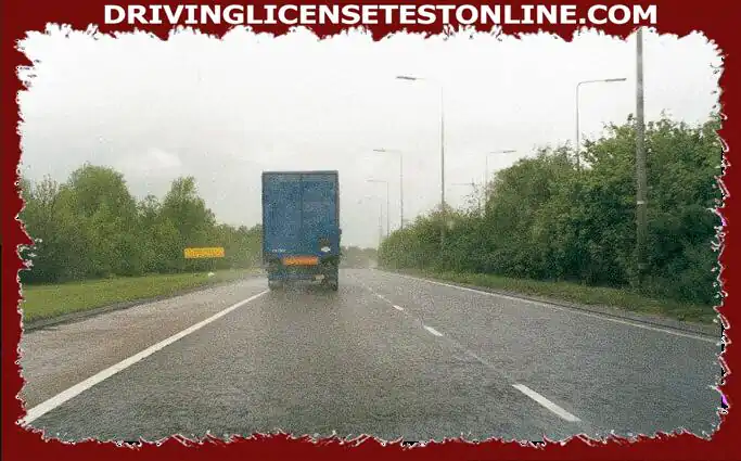 Je rijdt over deze snelweg. Het regent. Wat moet je doen als je deze vrachtwagen volgt?